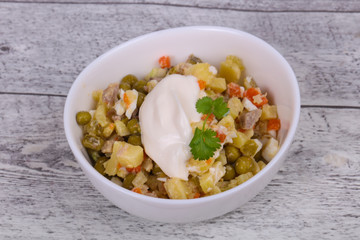 Traditional Russian salad with chicken in the white bowl