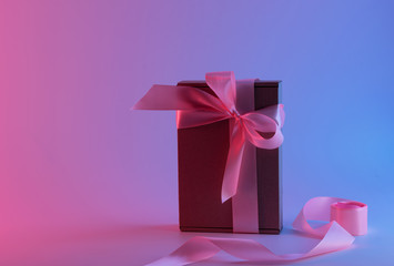 Gift box with pink ribbon in neon light