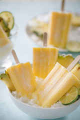 Some homemade Pineapple Popsicles (selective focus) on a rustic background