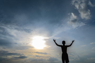 Fototapeta premium The boy raised his hand in the sky to ask for rain during the sunset.