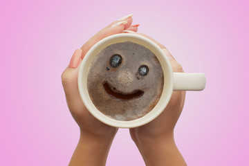 concept hand holding a  cup with smile coffee cream. Food art creative image on pink background.