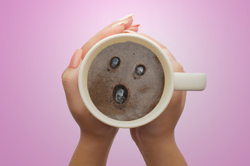 concept hand holding a cup with wow coffee cream. Food art creative image on pink background.