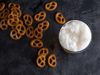 a glass of wheat beer with a traditional snack salty pretzel