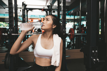 Fototapeta na wymiar Women after exercise drink water from bottles and handkerchiefs in the gym.