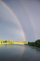 Double rainbow reflected on Ticino river. Cuggiono, Lombardia, Italy. Vertical shot.