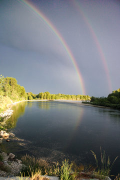 Double rainbow reflected on Ticino river. Cuggiono, Lombardia, Italy. Vertical shot.