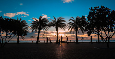 Relax on the beach, people strolling, enjoying the beautiful sunset.