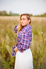 Beauty young woman in checkered shirt and white dress outdoors enjoying nature. Cowgirl style.