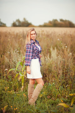 Beauty young woman in checkered shirt and white dress outdoors enjoying nature. Cowgirl style.