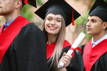 Happy students in bachelor robes outdoors