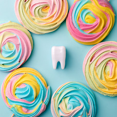 Plastic tooth in many colorfull rainbow sweetness from sugar. Caries and sugar concept. Dental care concept on blue background