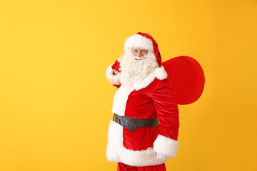 Fototapeta na wymiar Portrait of Santa Claus with bag on color background