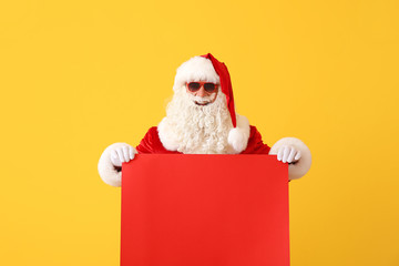 Portrait of cool Santa Claus with blank poster on color background