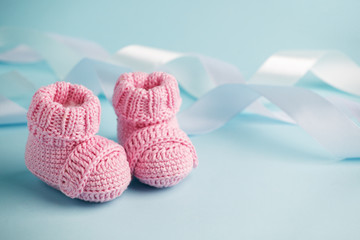 Pink Baby knitted shoes for newborns on blue background, Minimal baby shower, newborn party...