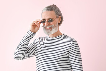 Fashionable senior man on color background