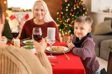 Happy little boy with his family having Christmas dinner at home