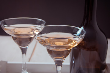 White wine in a glasses, bottle on the white wooden tray. Dinner for two.