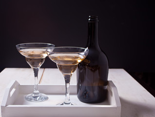 White wine in a glasses, bottle on the white wooden tray. Dinner for two.