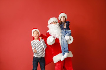 Santa Claus and little children showing thumb-up on color background