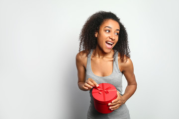 Portrait of beautiful African-American woman with gift box on white background