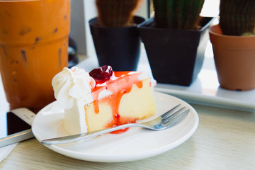 Slice cake with milk ice tea on wood table