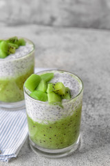 Glass with tasty kiwi dessert on grey background