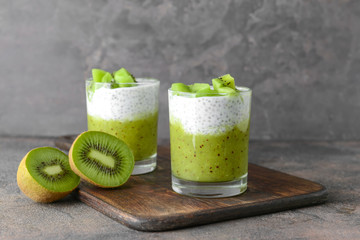 Glasses with tasty kiwi dessert on grey background