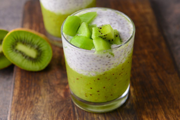 Glass with tasty kiwi dessert on wooden board