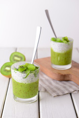 Glasses with tasty kiwi dessert on white table