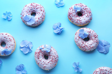 Sweet tasty donuts and flowers on color background