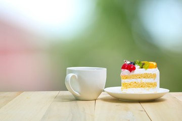 Slice cake with coffee cup on wood , green blur background