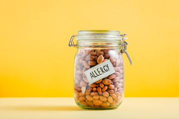 Glass jar full of peanuts with 'Allergy' sign in it. Food allergy and health concept - obrazy, fototapety, plakaty