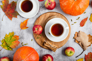 Autumn styled tea. Teacups, apples, pumpkins, cinnamon, and autumn leaves, top view