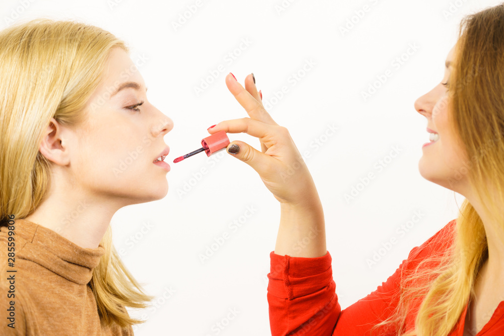 Poster Woman applying her friend lipstick on lips