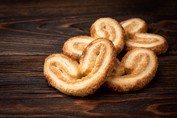 Palmier cookies or puff pastry ears on dark wooden background.