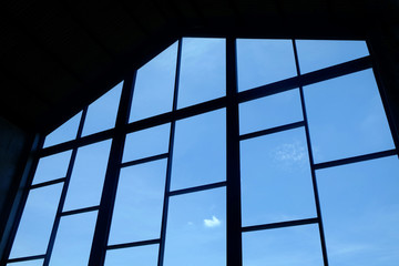 Silhouette of big window frames on a wall to outside blue sky