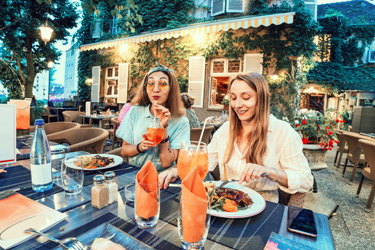Two women friends having lunch outside on terrace in french restaurant