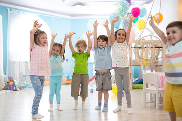 Fototapeta premium Happy kids with their hands up at daycare or children club
