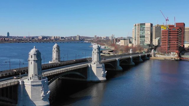 Aerial establishing city skyline of Cambridge Boston Massachusetts with Longfellow bridge and subway train crossing.