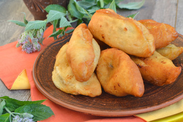Hot fresh pies on a ceramic plate with orange napkin and fresh mint, close up © chaiko