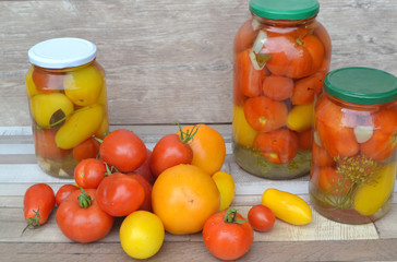 glass jar of canned tomatoes in red and yellow colors on rustic table, russian cuisine