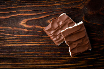 Chocolate bar with coconut filling on dark wooden background.