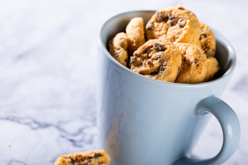 Chocolate chip cookies in blue cup on marble stone background. Selective focus. Copy space.