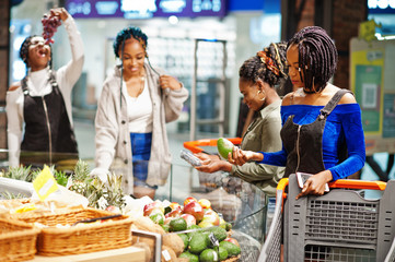 Group of african womans with shopping cart buying exotic fruits in grocery store supermarket.