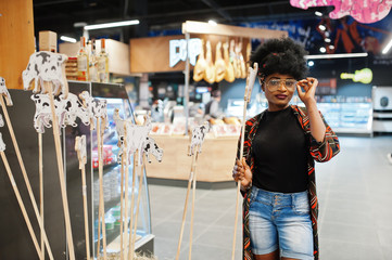 African woman in the milk department of the supermarket with cow sticks.