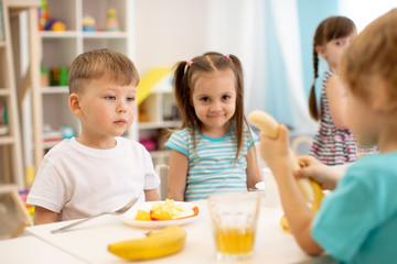 Obraz na płótnie Canvas Kids have a lunch in daycare centre. Children eating fresh fruits in kindergarten