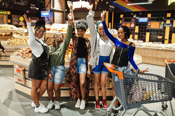 Group of african womans with shopping carts near baked products at a supermarket.