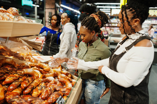 Group of african womans with shopping carts near baked products at a supermarket.