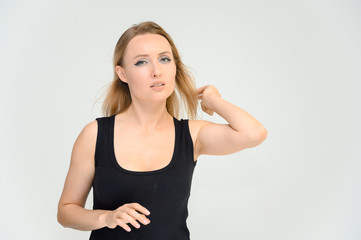 Studio waist-length photo portrait of a pretty beautiful young happy blonde woman on a white background in a black t-shirt. Smiling, talking, showing emotions.