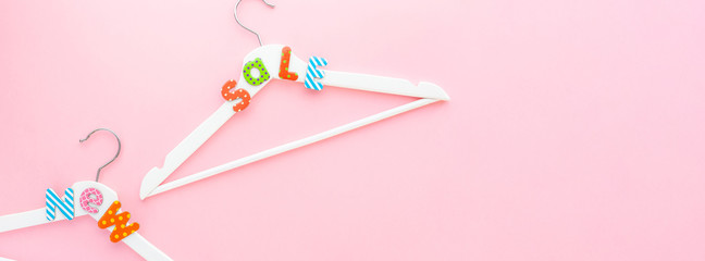White hangers with sale text on pink background